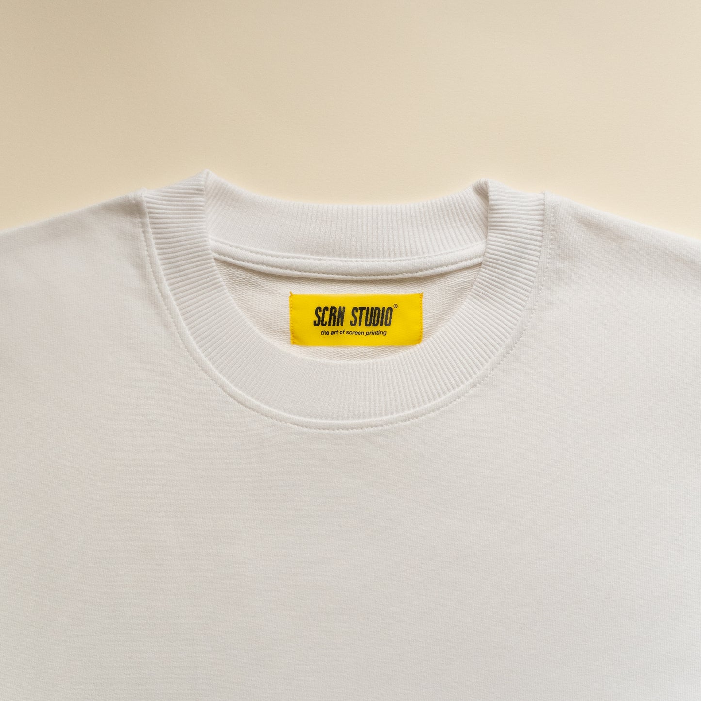 White tshirt with a yellow label on a beige background