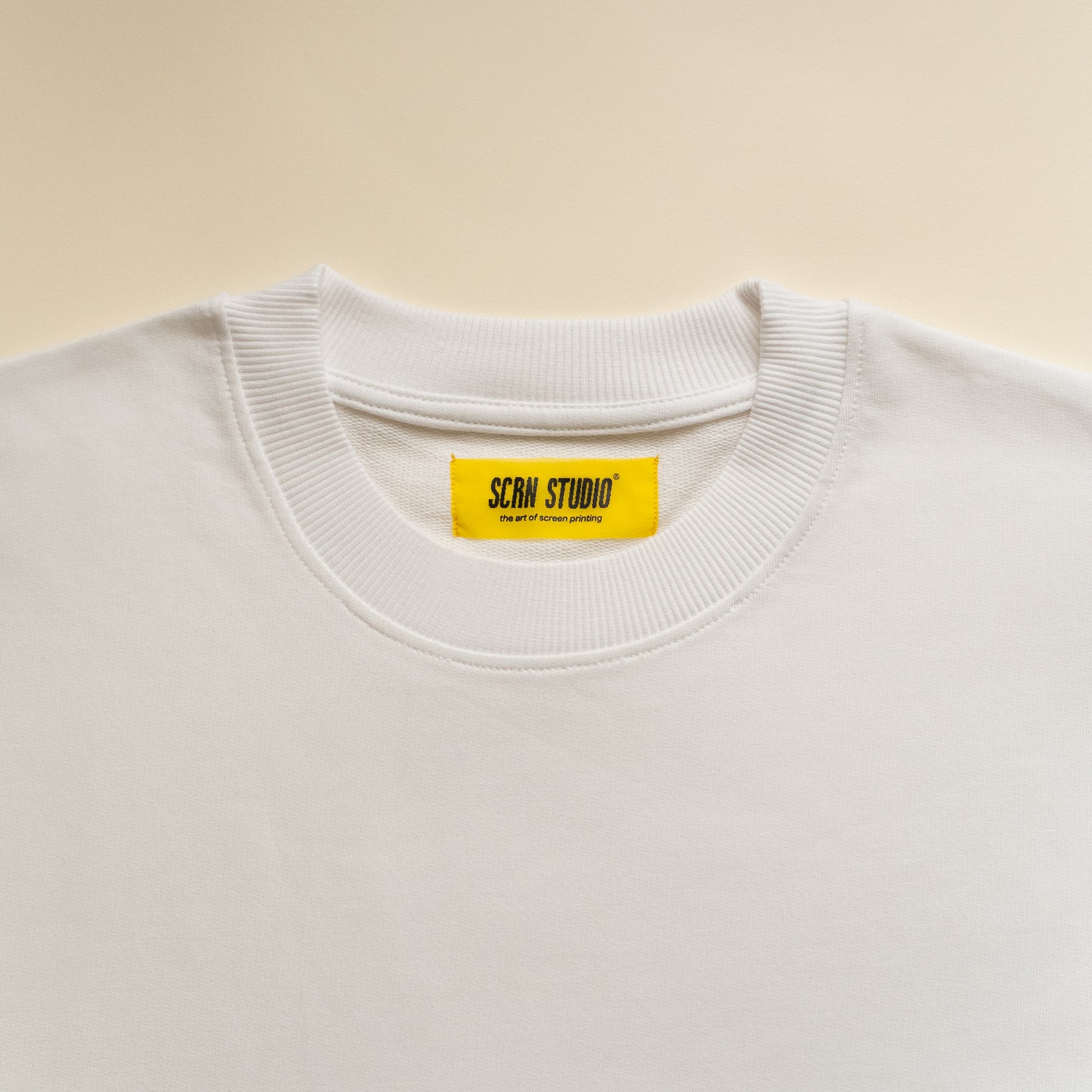 White tshirt with a yellow label on a beige background